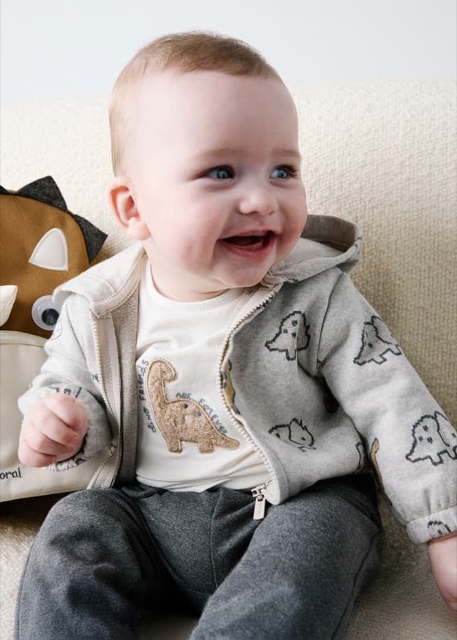 Smiling toddler in a Mayoral dinosaur hoodie set